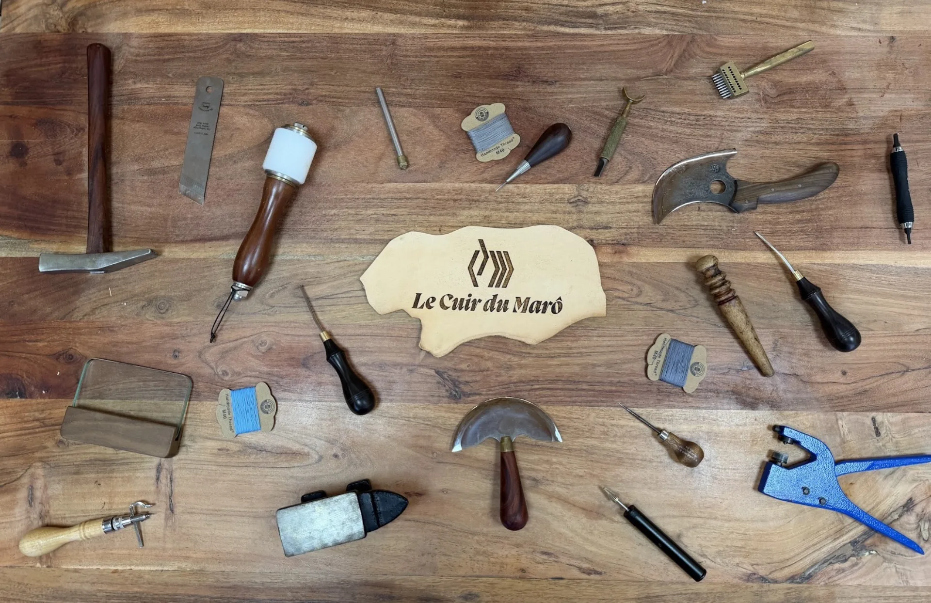 Établi de l'atelier — outils de maroquinerie autour d'une pièce de cuir gravée « Le Cuir du Marô »